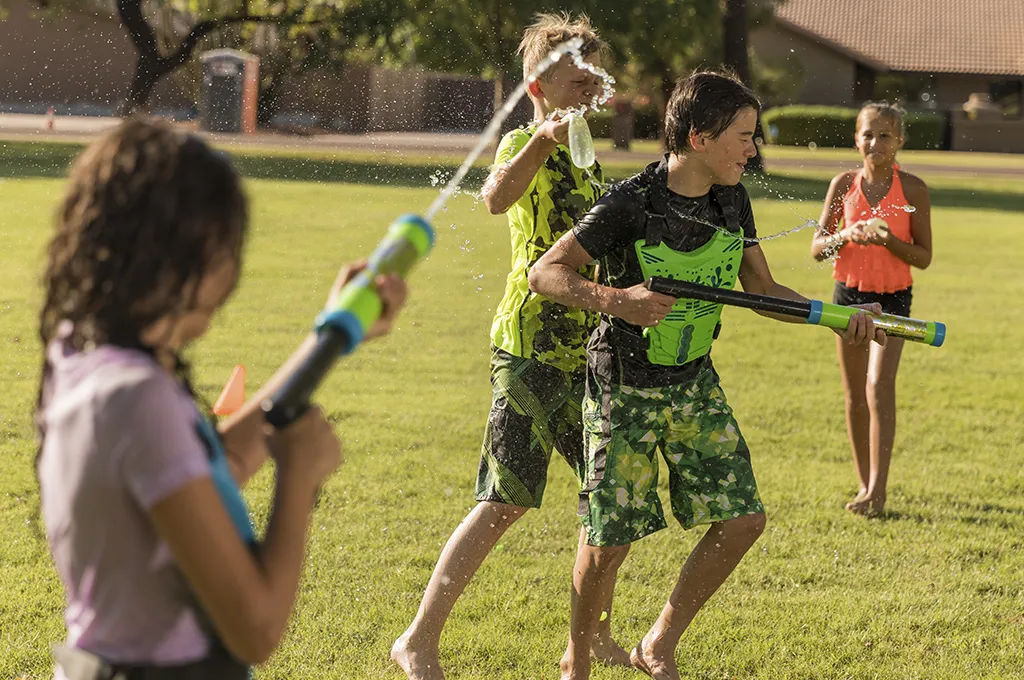 Kids playing with water guns at a GameTruck Water Tag party, getting soaked and having fun
