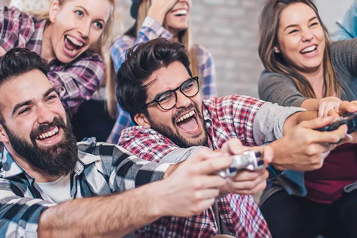 Coworkers laughing and competing on PlayStation controllers at a Gameplex corporate event