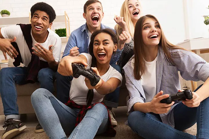 Group of teenagers laughing and cheering while playing video games at a Gameplex event